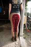Back View - Women's tan breeches with full seat in red and fox print pattern. Model stands in barn doorway wearing signature V-Neck womens riding t-shirt in black with the breeches.
